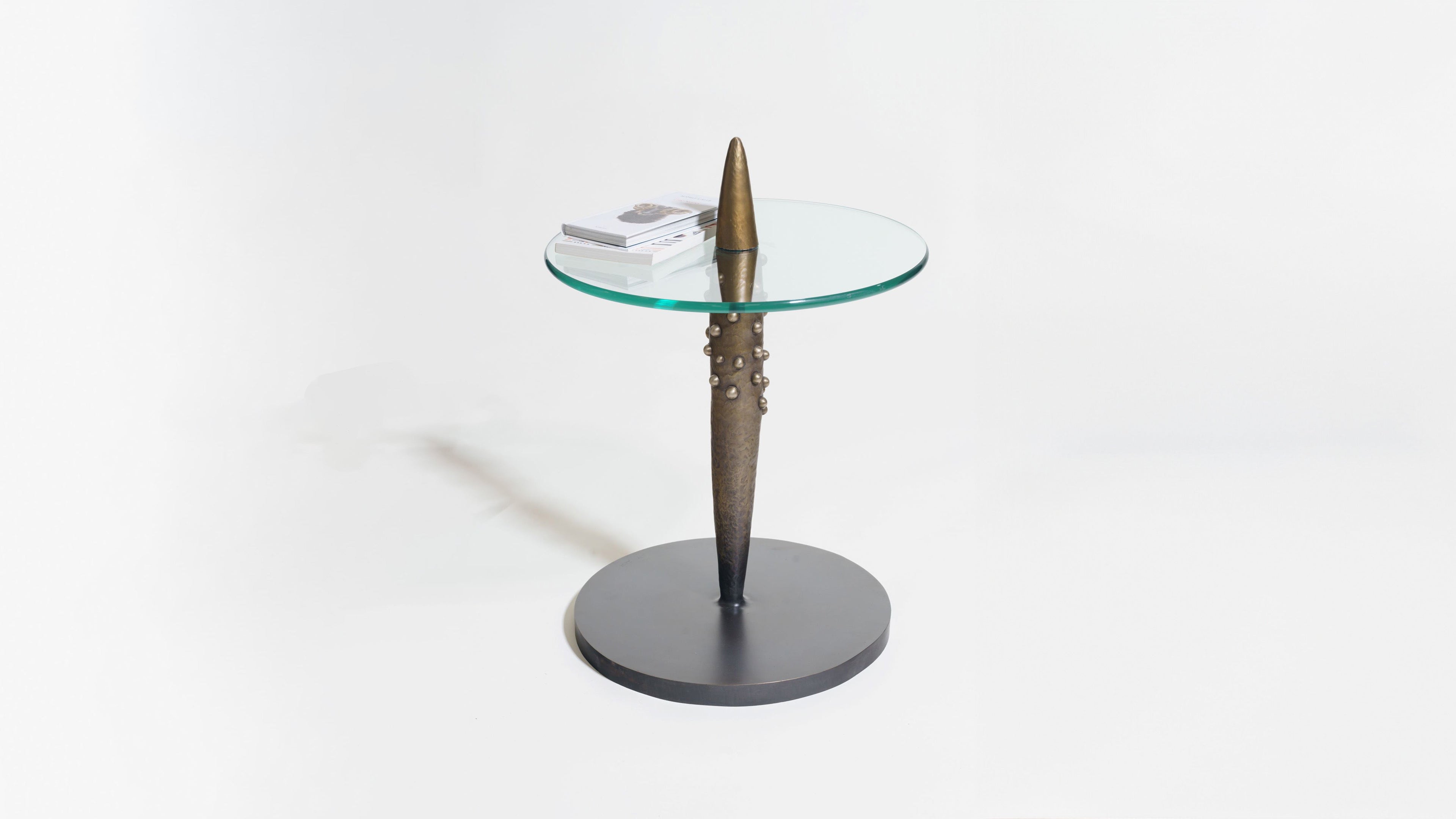 Glass side table with unique metallic base on a white background